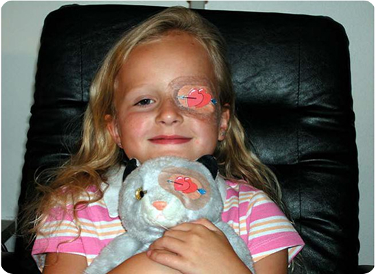 Ребенок с глазной повязкой и игрушкой